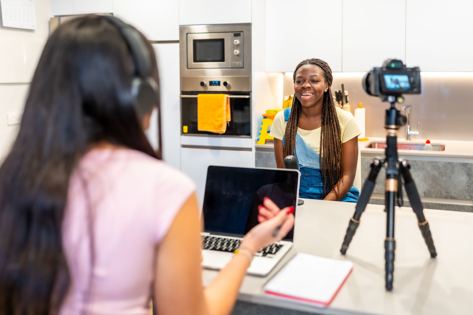 Teenage girls creating video content at home using laptop and camera